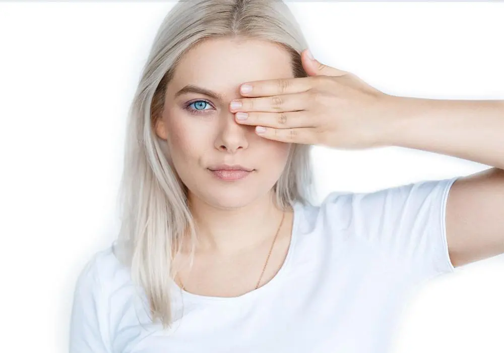 Frau hält sich mit einer Hand ein Auge zu